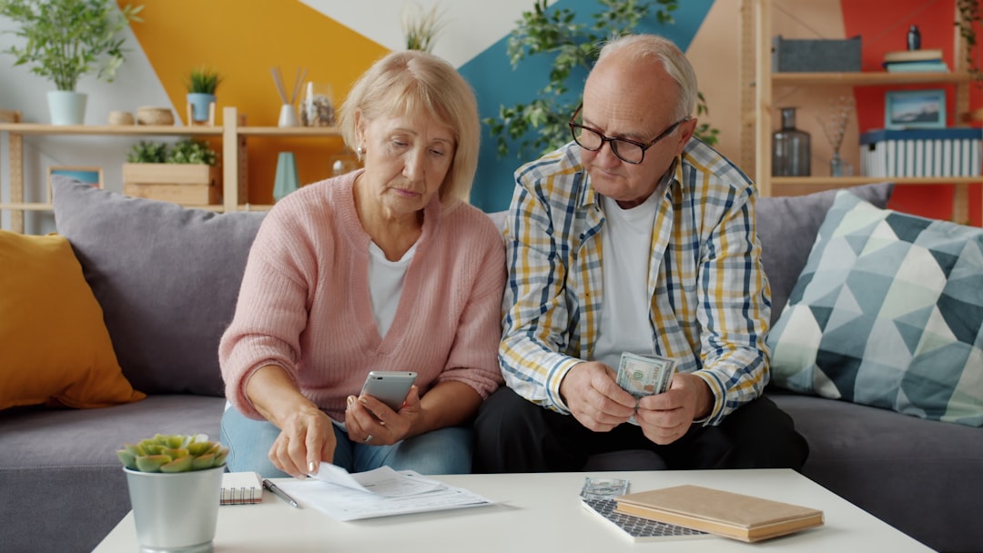 Retired man and woman counting money reading financial document at home dealing with bills and loans. Retirement, finance and lifestyle concept.